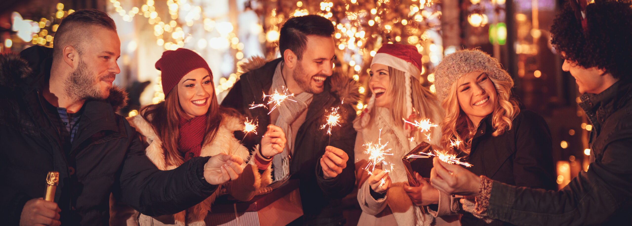 Gäste stoßen mit Wunderkerzen und Getränken bei einer Weihnachtsfeier an Deck an