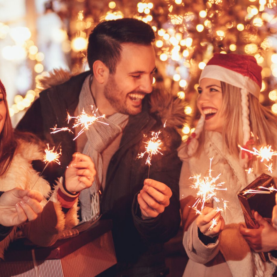 Gäste stoßen mit Wunderkerzen und Getränken bei einer Weihnachtsfeier an Deck an